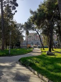 Footpath amidst trees and buildings against sky