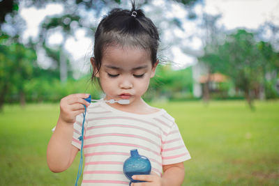 Cute girl blowing bubbles while playing at park