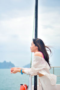 Rear view of young woman standing against sky