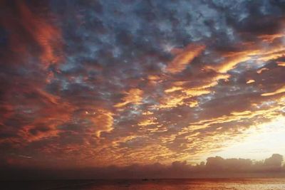 Scenic view of sea against cloudy sky at sunset