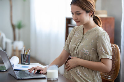 Young woman using mobile phone while sitting on table