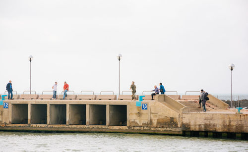 Men on pier in sea against sky