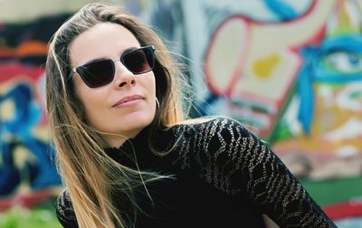 Young woman wearing sunglasses against graffiti wall