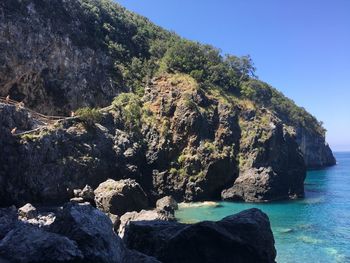 Rock formations by sea against clear sky
