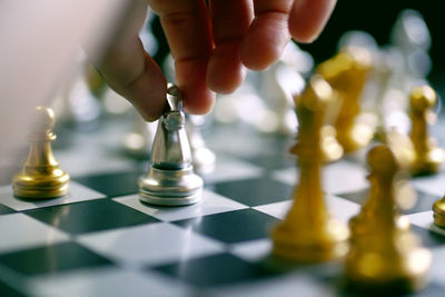 Close-up of person holding chess piece on board