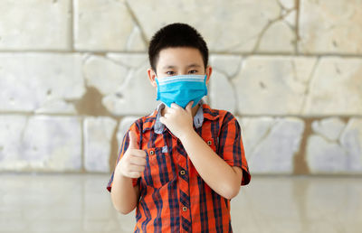 Portrait of boy standing against wall