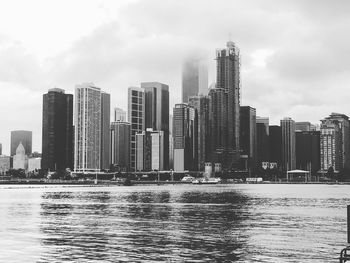 River by modern buildings against sky in city