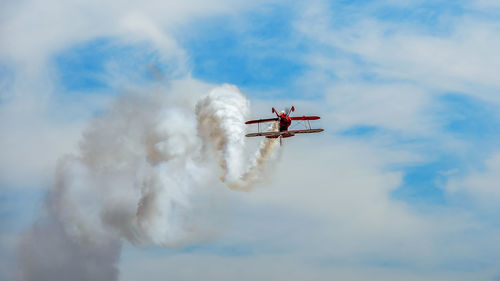 Low angle view of air vehicle flying against cloudy sky