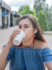 Young woman drinking coffee at street