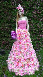 Full length of woman standing by pink flowering plants