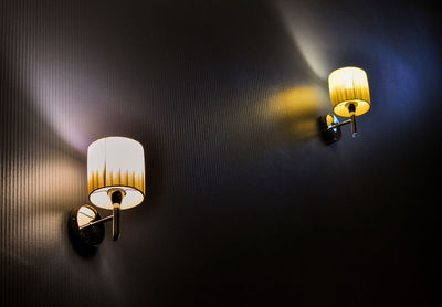 Low angle view of illuminated lamp mounted on wall