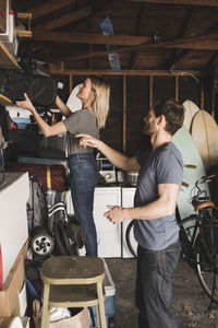 Mid adult couple arranging bag on shelf in storage room