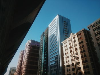 Low angle view of skyscrapers against blue sky