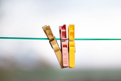 Close-up of colorful clothespins on clothesline against sky
