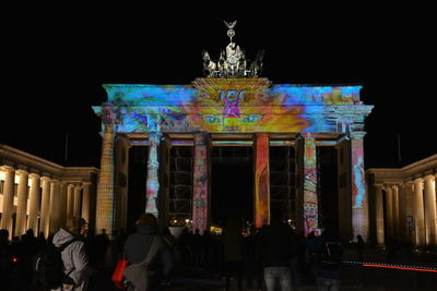 Group of people in front of illuminated building at night