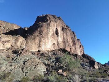 Low angle view of rock formation against clear blue sky