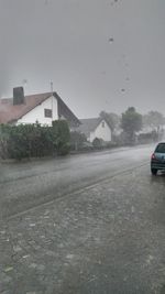 Cars on road by buildings against sky