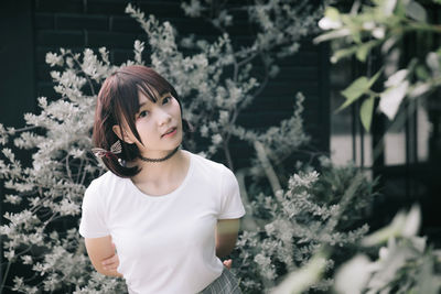 Portrait of beautiful woman standing by flower plants