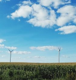 Wind turbines in field against sky