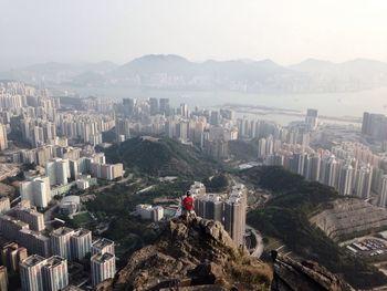 Man on top of peak with city in background