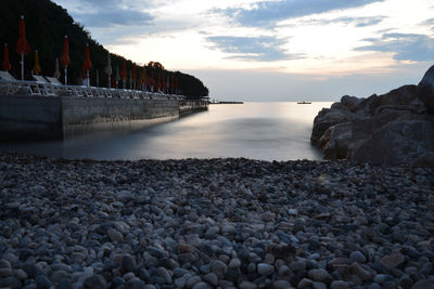 Rocks on beach against sky during sunset