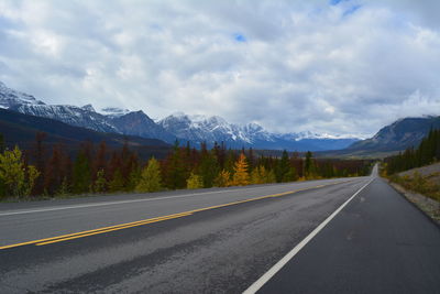 Empty road by mountains against sky