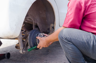 Midsection of man repairing car wheel