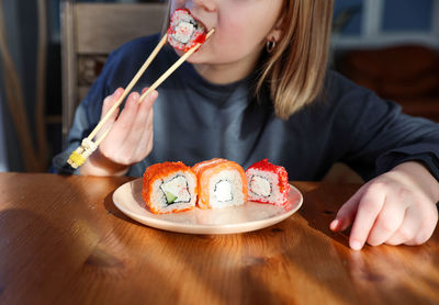 Girl eats sushi, rolls at the table