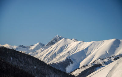 Scenic view of snowcapped mountains against clear blue sky