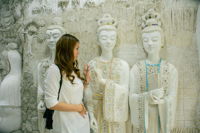 Woman by buddha statues on wall