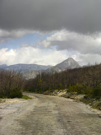 Road by mountains against sky