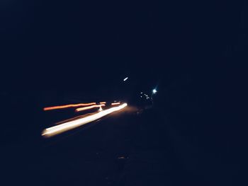 Light trails on road against clear sky at night