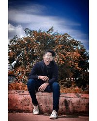 Portrait of young man sitting on plant against trees