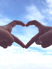 Close-up of hand holding heart shape against sky