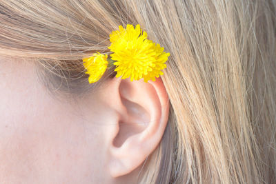 Close-up of yellow flower on hair of woman