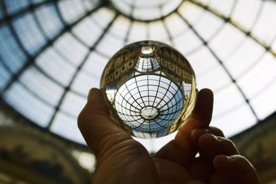 Close-up of hand holding crystal ball against monument ceiling 