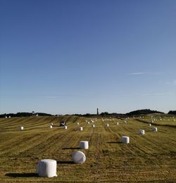 Hay bales on field against clear sky