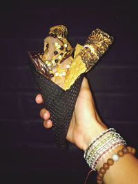 Close-up of woman holding ice cream cone against black background