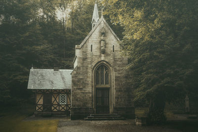 Old building by trees against sky