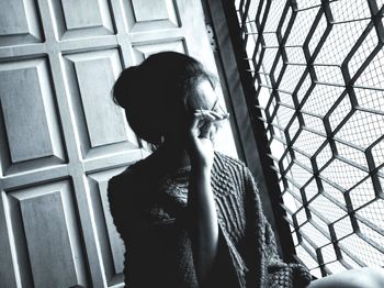 Portrait of woman standing against window