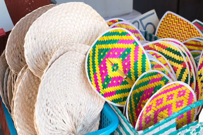Close-up of straw hand fans in containers for sale at store