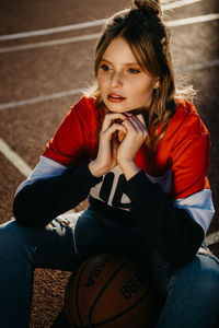 High angle view of thoughtful young woman sitting on court