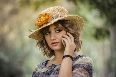 Portrait of young woman in hat talking on mobile phone