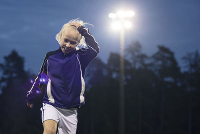 Happy girl walking with hand in blond hair against sky