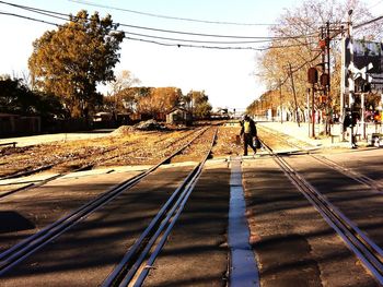 Man walking on railroad tracks against clear sky