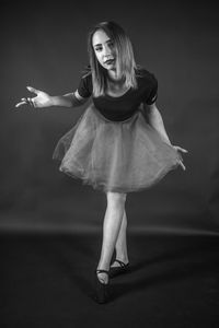 Portrait of ballet dancer standing against gray background