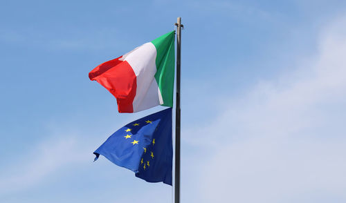 The italian flag waves with the european union flag.