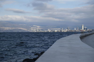 Sea by buildings against sky in city