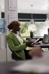 Side view of woman using mobile phone while sitting on table