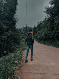 Rear view of man walking on dirt road